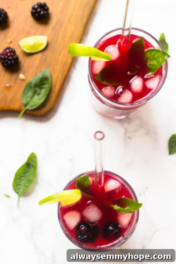 Top-down shot of vibrant blackberry limeade in two glasses with straws, highlighting its refreshing appeal.