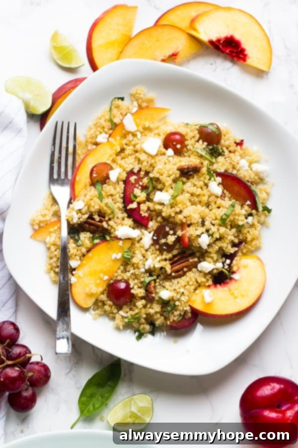 Overhead shot of quinoa stone fruit salad on a square white plate with a fork on the side. 