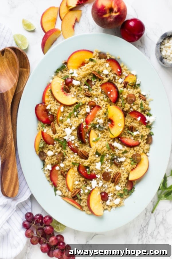 Top-down shot of quinoa stone fruit salad with wooden utensils on the side. 