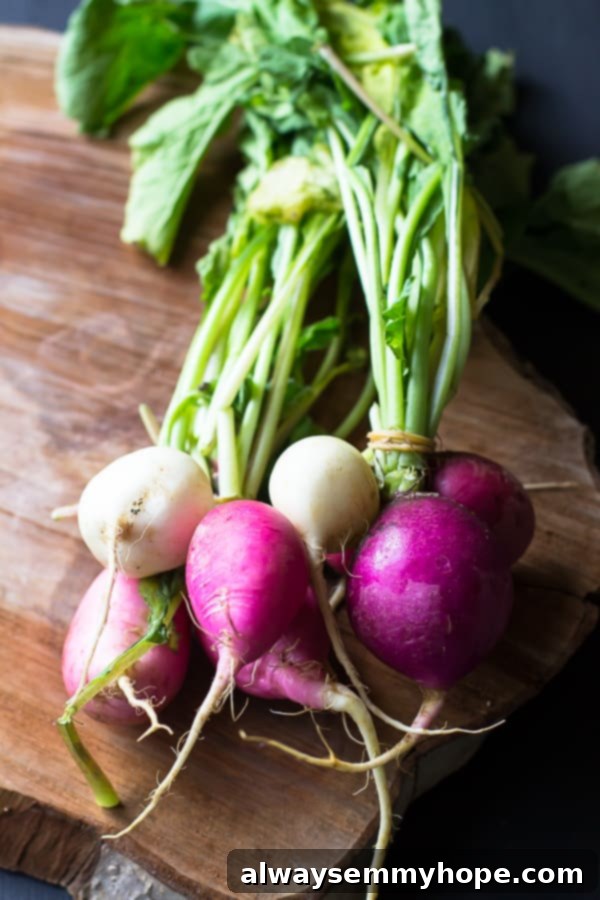 A vibrant batch of fresh Easter Egg radishes with their green tops, arranged on a rustic wooden block.