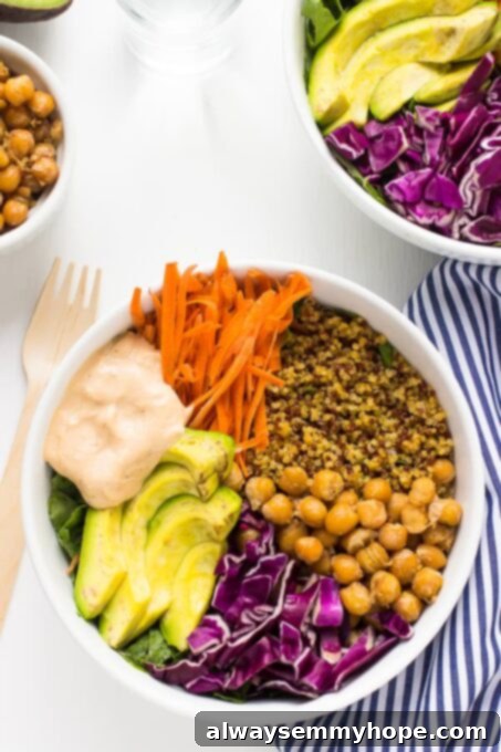A top-down shot of a colorful nourish buddha bowl featuring avocado slices, grains, and vegetables, with a striped dish cloth on the side.