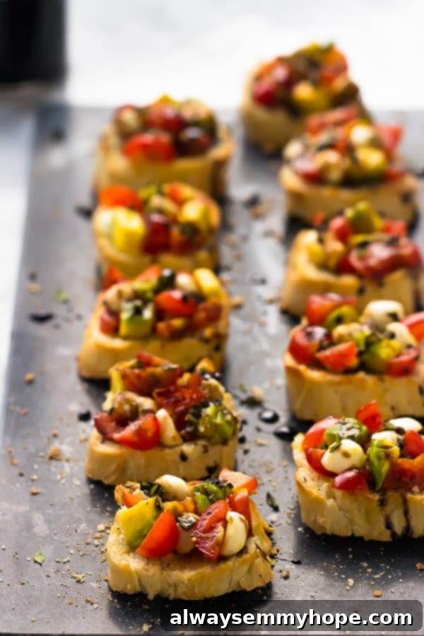 Rows of avocado caprese bruschetta beautifully presented on a unique grey soapstone serving tray.
