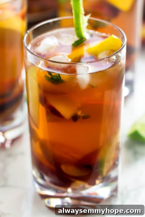 Glass of peach sangria with plums and basil