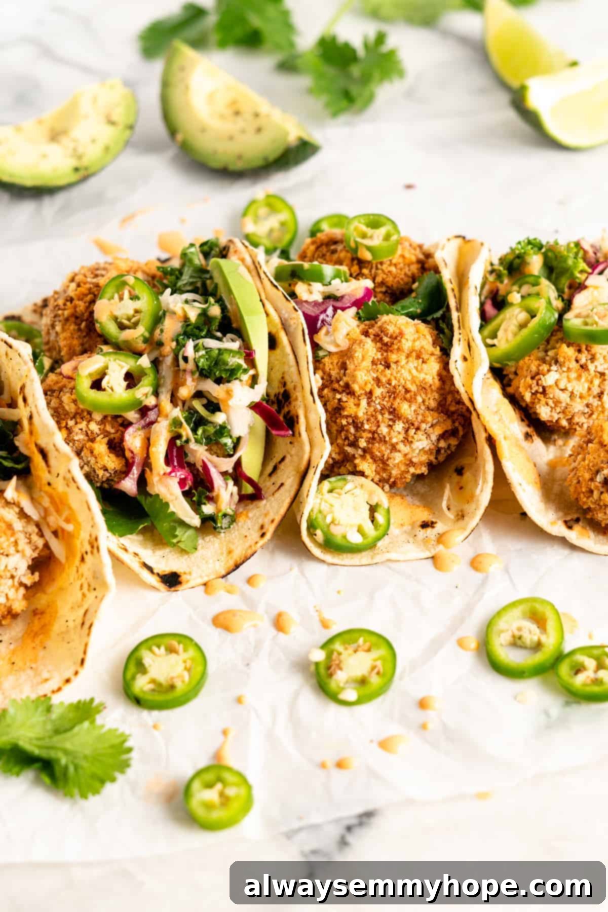 Crunchy Cauliflower Tacos with Smoky Chipotle Crema 2 Side view of vegan tacos filled with crispy breaded cauliflower, vibrant slaw, fresh avocado, and sliced jalapeños