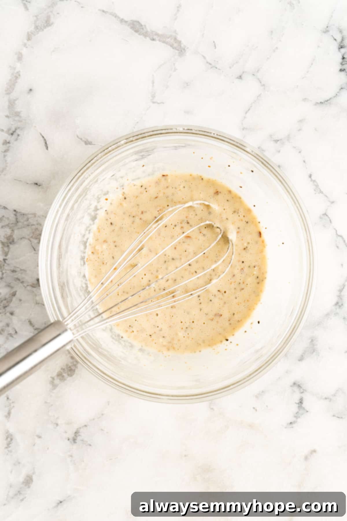 Crunchy Cauliflower Tacos with Smoky Chipotle Crema 5 Overhead view of a glass bowl containing the smooth, seasoned batter for cauliflower, with a whisk resting in it