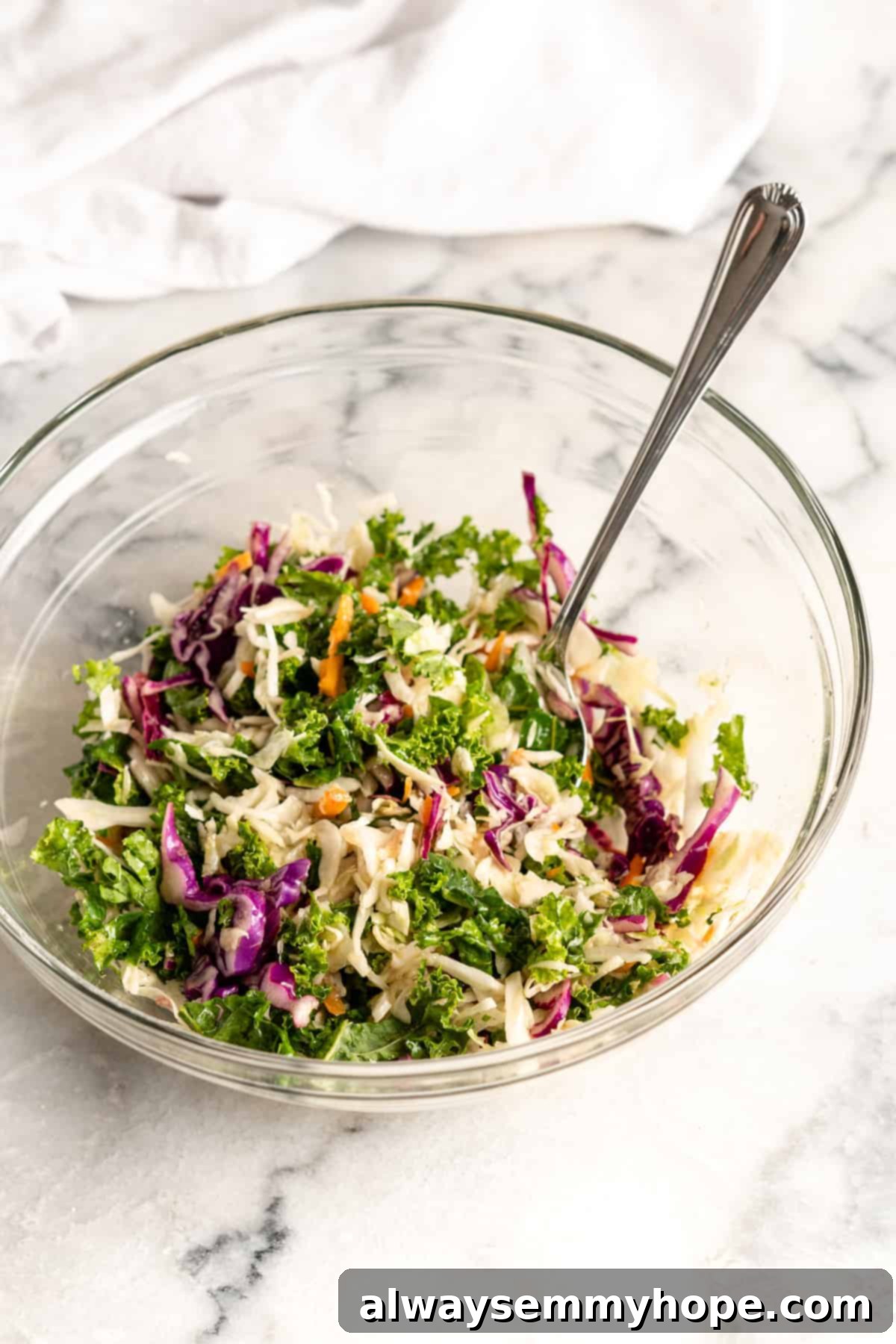 Crunchy Cauliflower Tacos with Smoky Chipotle Crema 7 Freshly mixed kale and cabbage slaw in a glass bowl with a serving spoon
