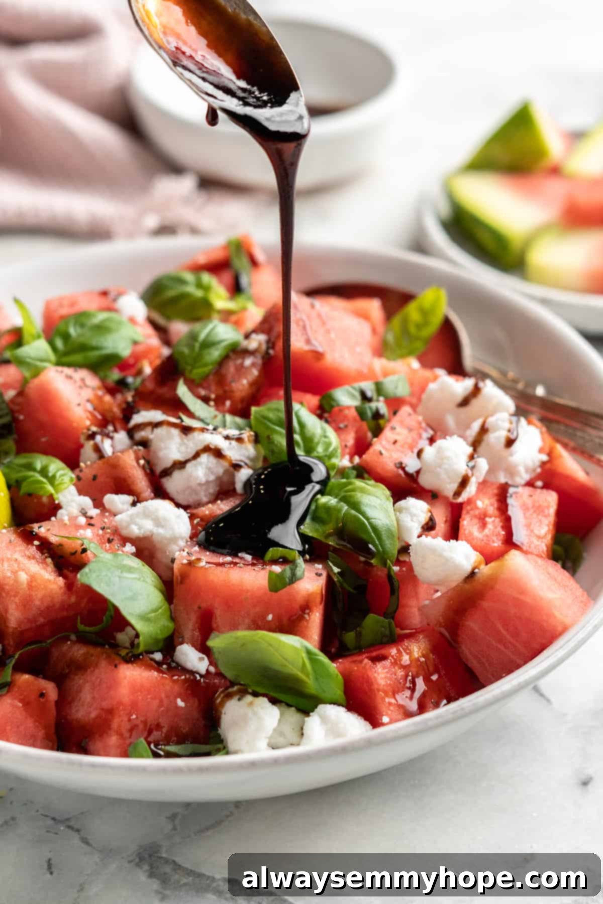 Pouring balsamic drizzle over vegan watermelon feta salad