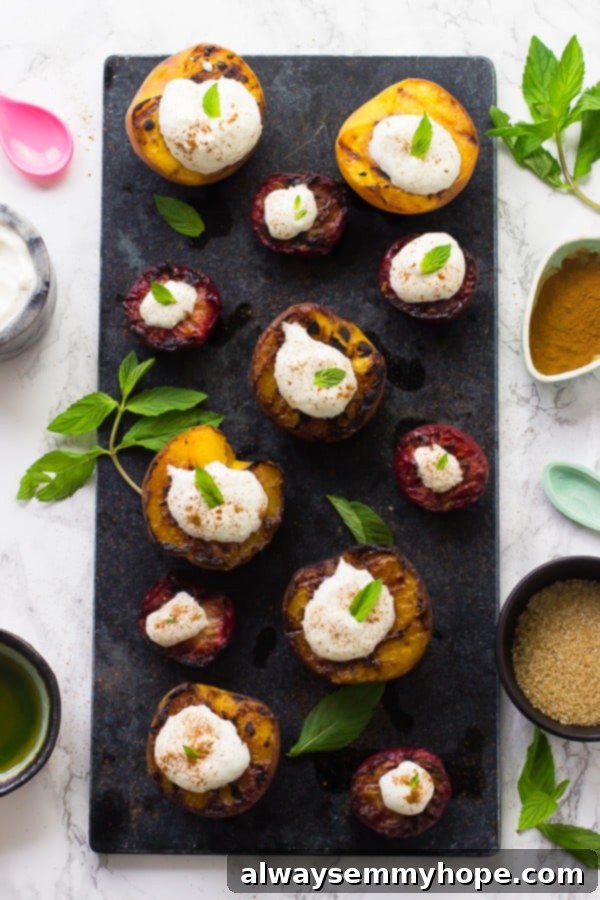 Flame-Kissed Fruit with Coconut Dream 3 Overhead shot of vibrant grilled stone fruit, including peaches and plums, generously topped with fluffy white coconut cream, presented on a chic grey slate background, highlighting a perfect, quick summer dessert.