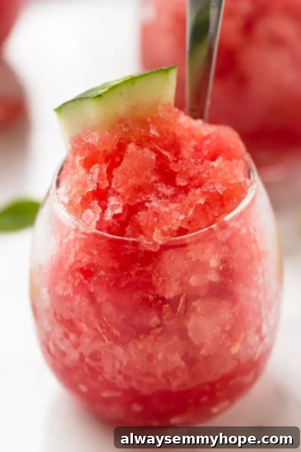 Close up of watermelon granita in a glass with a spoon in it. 