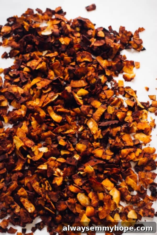 These gluten-free vegan bacon crumbles are made out of coconut, and taste just like real bacon. They're salty, smoky, and sweet! A top-down view of perfectly crispy and golden coconut bacon crumbles scattered invitingly on a clean white countertop, ready to be enjoyed.