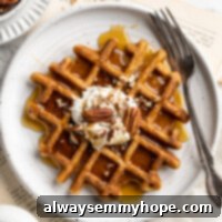 Spiced Pumpkin Waffles 3 Overhead view of a pumpkin waffle on a plate with a fork, topped with coconut cream and pecans