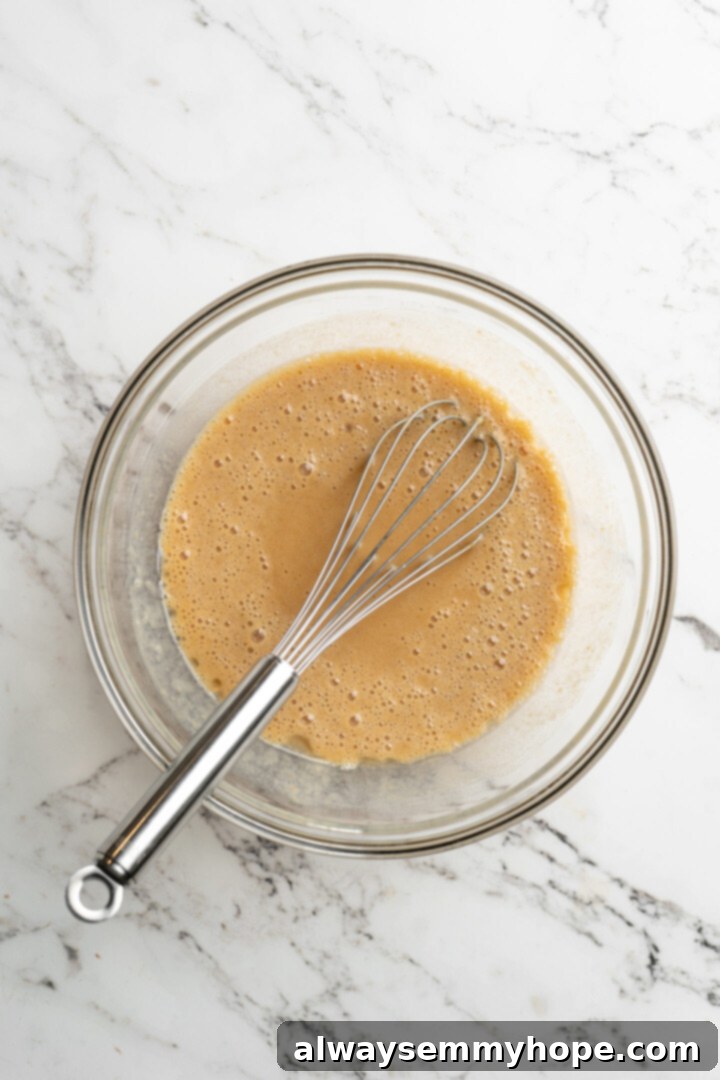 These easy vegan pumpkin waffles are light, fluffy, and crispy, with your favorite fall flavors, and can easily be made gluten-free. A mixing bowl with a wet pumpkin mixture and a whisk