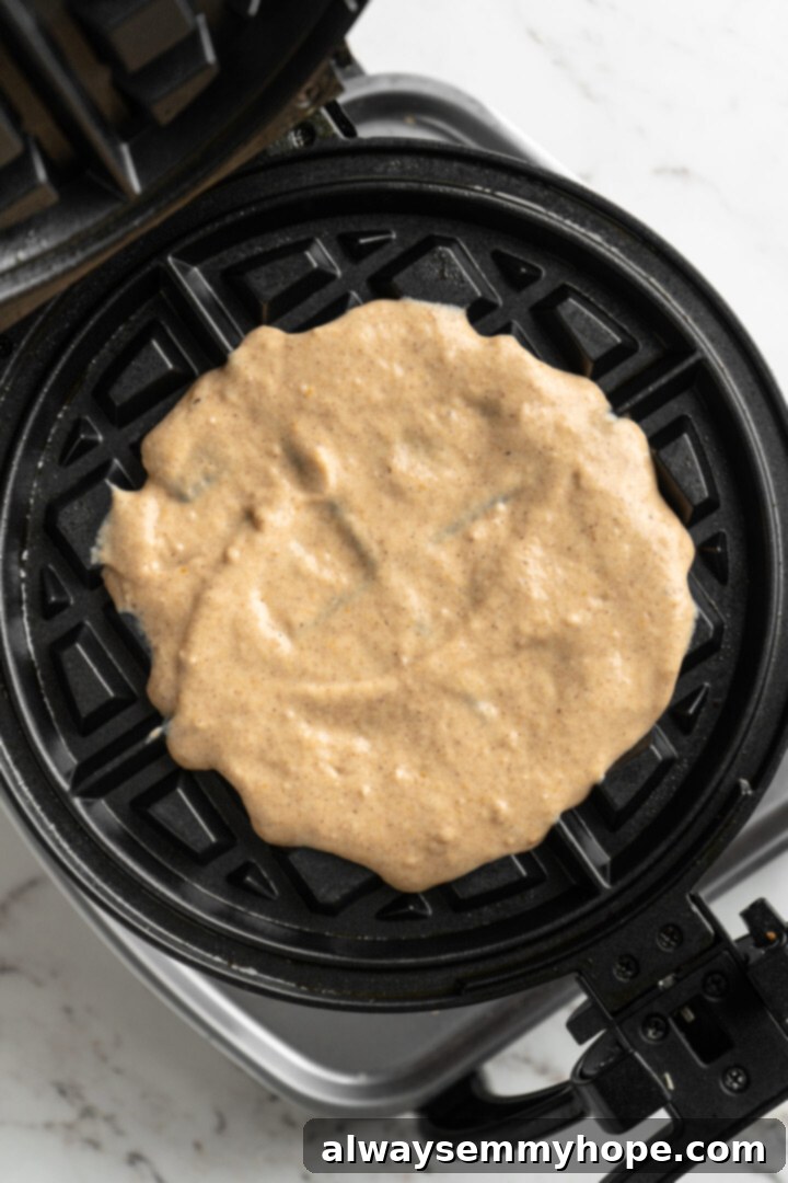 These easy vegan pumpkin waffles are light, fluffy, and crispy, with your favorite fall flavors, and can easily be made gluten-free. Waffle batter in a waffle iron