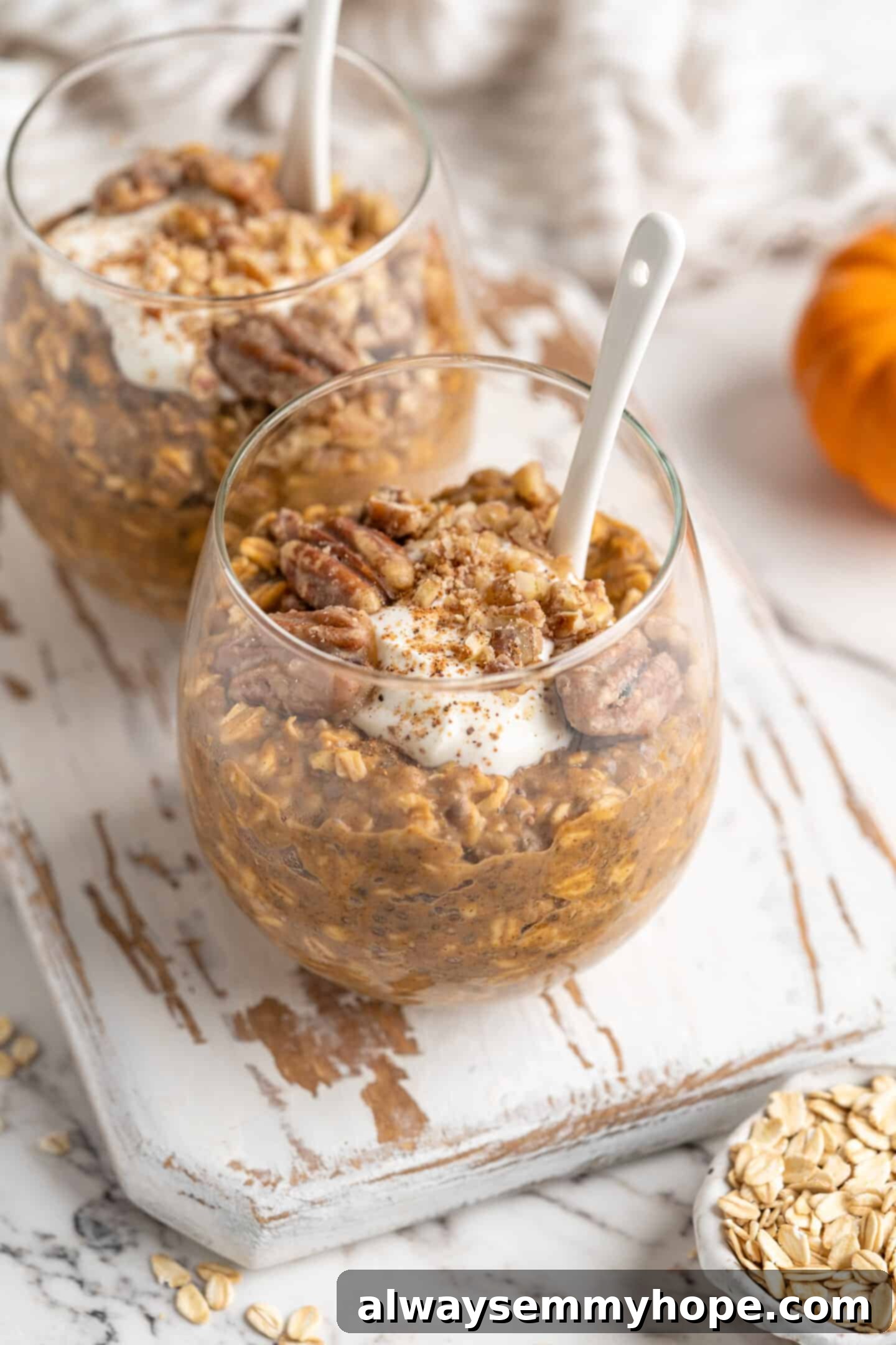 two jars of pumpkin pie overnight oats with spoons inside 45 degree angle shot, ready for a cozy fall morning breakfast