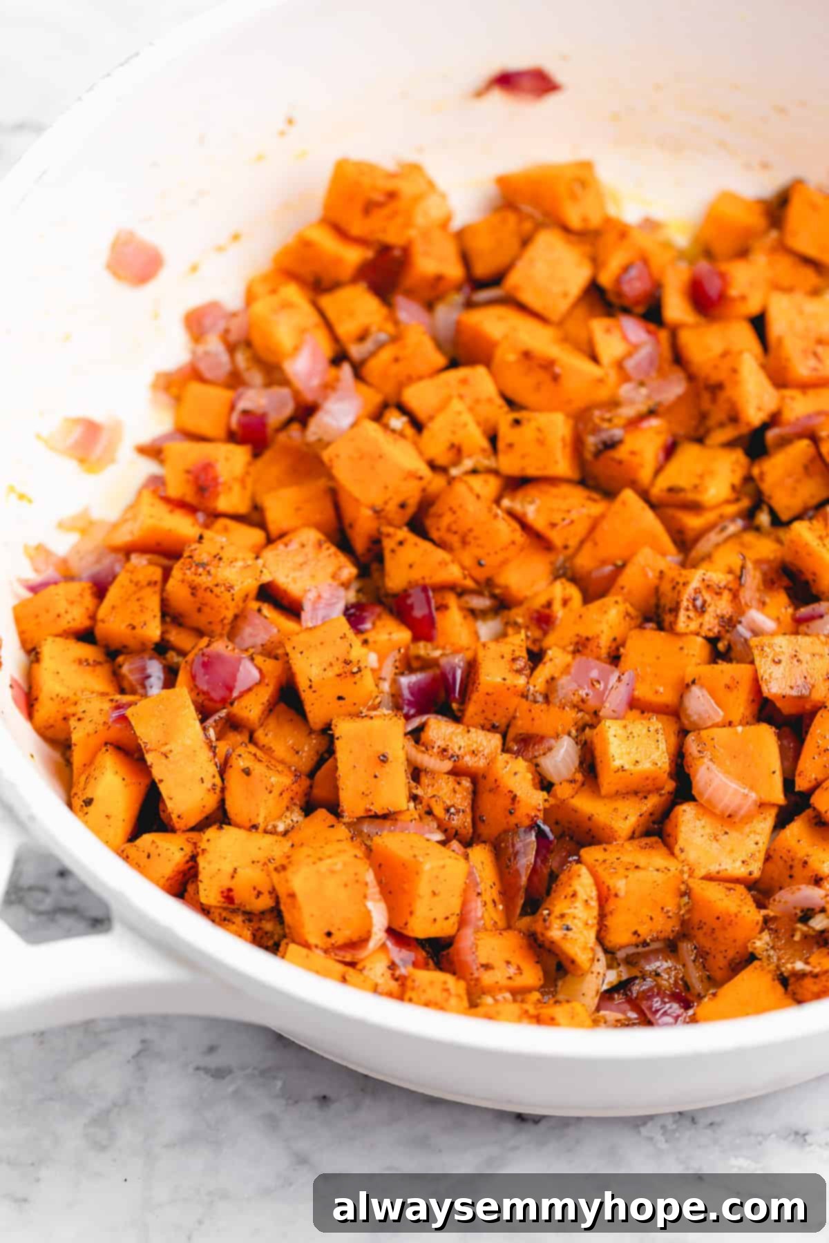 Pan of sautéed red onion and sweet potatoes.