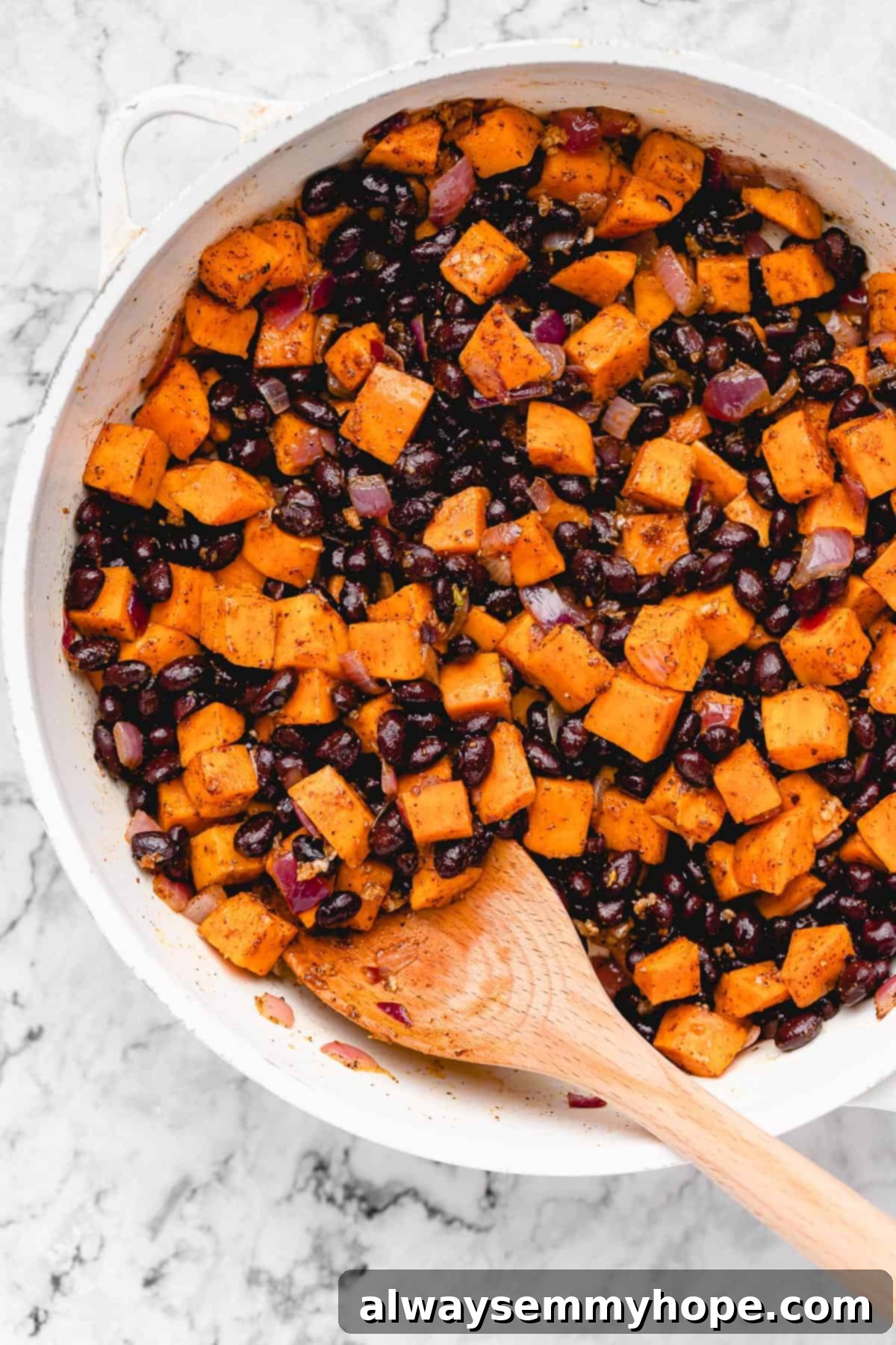 Chopped sweet potato with black beans in a pan.