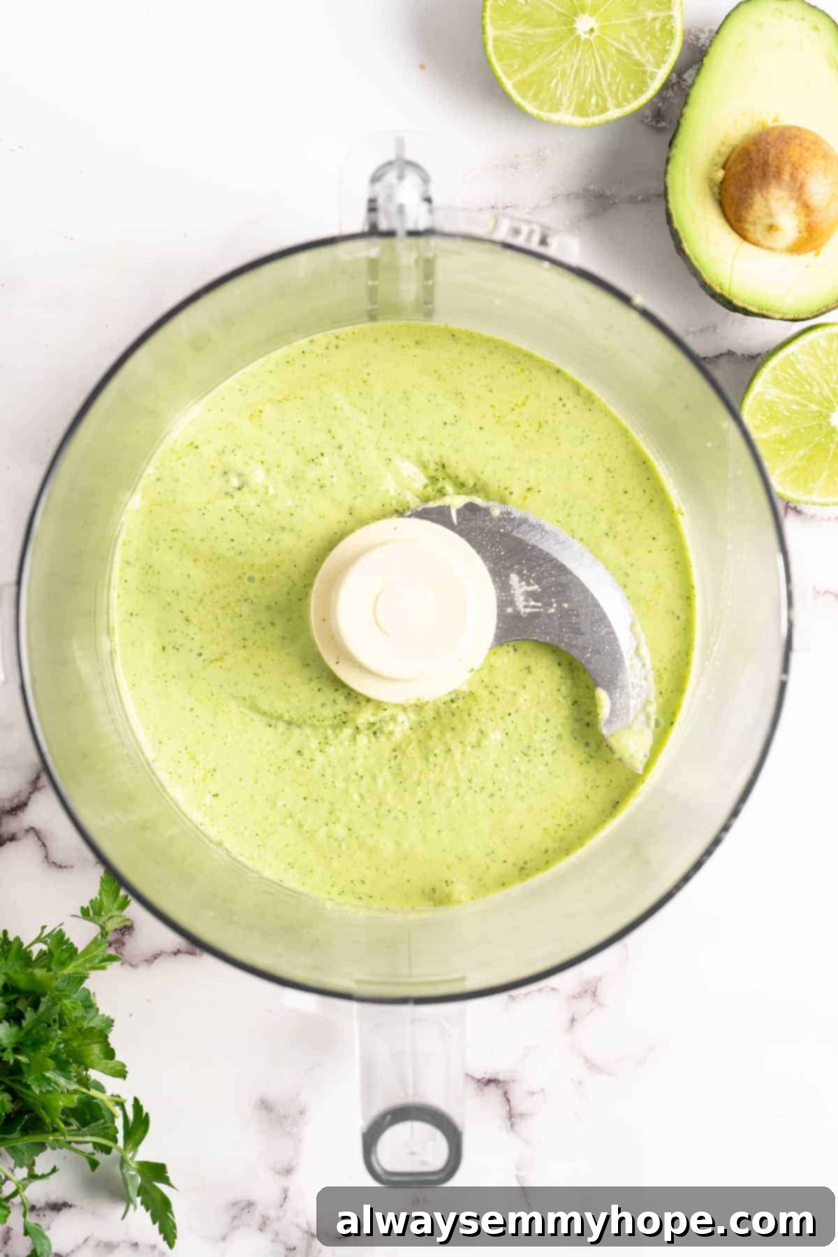 Naturally Creamy Vegan Avocado Dressing 5 Smooth and vibrant green creamy vegan avocado dressing being processed inside a high-speed food processor, indicating a successful blend.