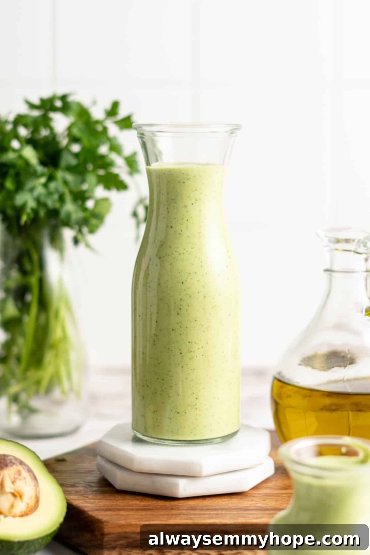 Naturally Creamy Vegan Avocado Dressing 9 A single tall glass jar filled with luscious, vibrant green creamy vegan avocado dressing, showcasing its smooth texture.