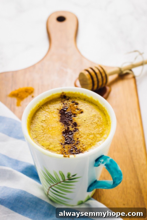 Pumpkin Golden Milk is a fun twist on classic turmeric milk. Ready in just minutes, this vegan drink is the perfect night cap! A warm mug of Pumpkin Golden Milk Latte, garnished with cinnamon, resting on a rustic wooden board, perfect for a cozy evening.
