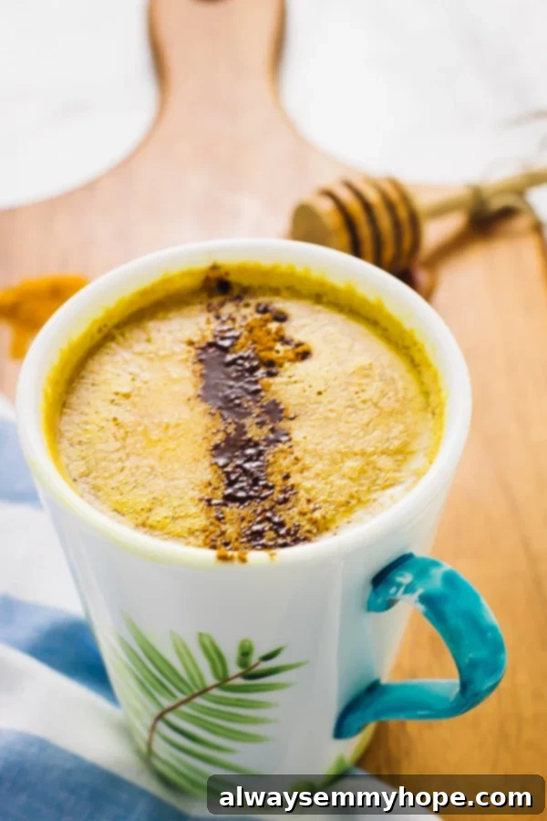 Pumpkin Golden Milk is a fun twist on classic turmeric milk. Ready in just minutes, this vegan drink is the perfect night cap! Close up shot of creamy Pumpkin Spice Golden Milk in a mug on a wooden board, highlighting the rich golden color and inviting texture.