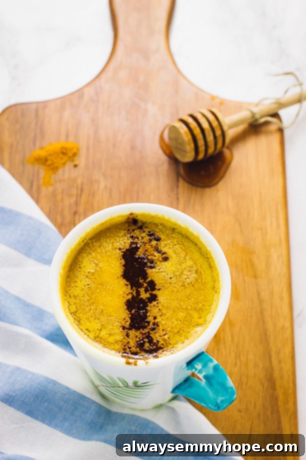 Pumpkin Golden Milk is a fun twist on classic turmeric milk. Ready in just minutes, this vegan drink is the perfect night cap! Overhead shot of a vibrant Pumpkin Golden Milk Latte served in a stylish white and blue mug, placed on a wooden board, ready to be enjoyed.
