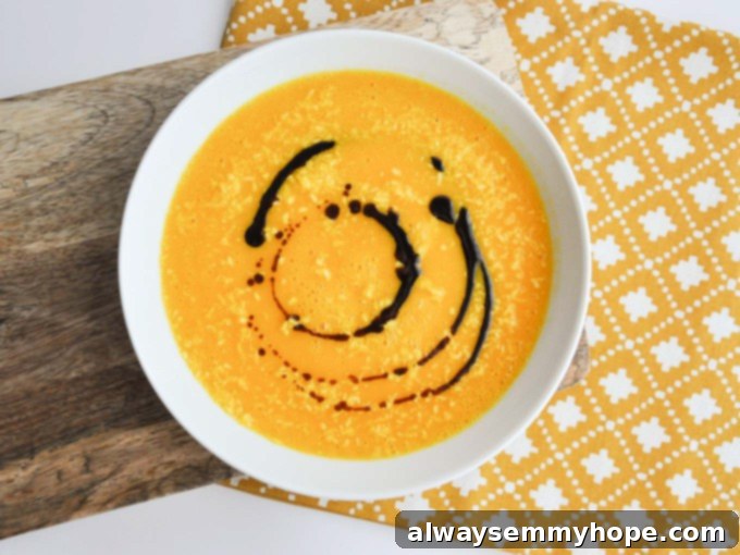Quick Fall Vegan Dinners: 25 Recipes Ready in 15 Minutes 16 Overhead shot of a bowl of creamy vegan carrot ginger soup on a yellow tablecloth, garnished with fresh herbs.