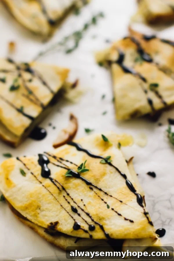 Close up of pear brie & caramelised onions quesadillas drizzled with a balsamic glaze, highlighting the crispy tortilla and melted cheese.