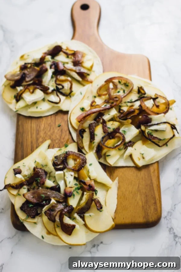 Three tortillas laid out, each with slices of fresh pear and creamy brie cheese, ready for the next step of assembly.