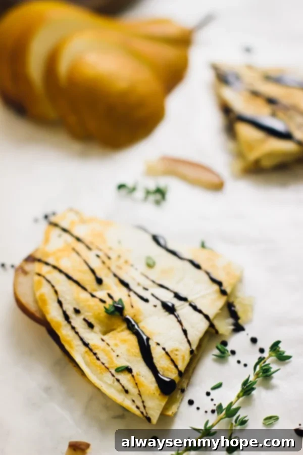 A perfectly triangular slice of pear brie & caramelised onions quesadilla, showing the melted cheese and pear layers, generously drizzled with balsamic glaze.