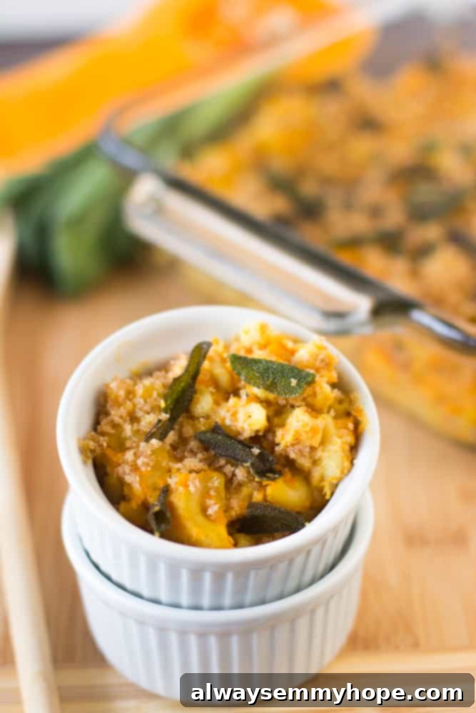 Creamy vegan butternut squash mac and cheese in a small ramekin, garnished with crispy sage, on a rustic wooden table top.