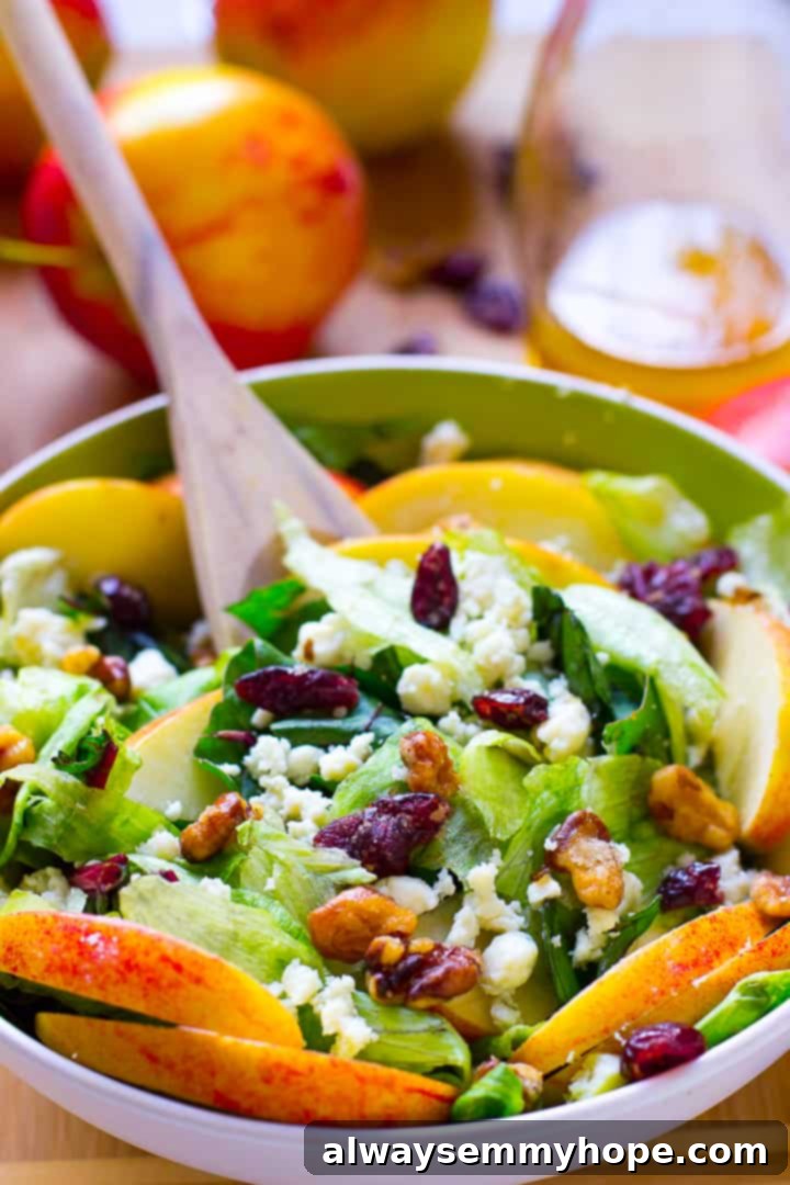 A wooden spoon stirring a fresh apple salad with a light dressing, featuring crisp apple slices.