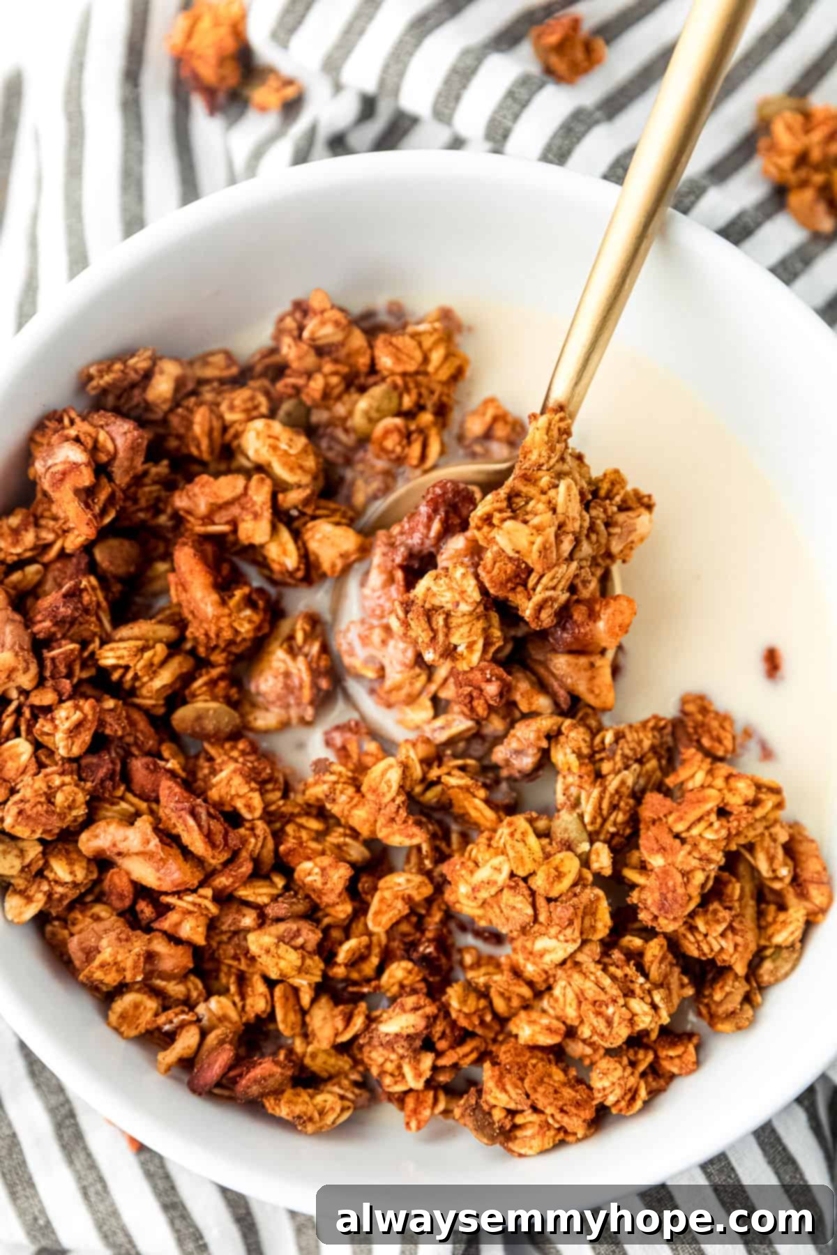 A bowl of delicious pumpkin granola soaked in milk, with a spoon ready for enjoyment, showcasing its golden-brown texture and appealing clumps.