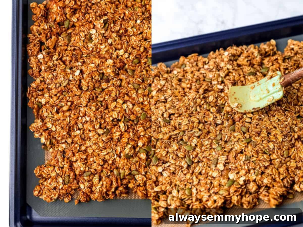 The pumpkin granola mixture is spread evenly onto a parchment-lined baking sheet, ready for the oven, with a spatula used to press it down for clumps.