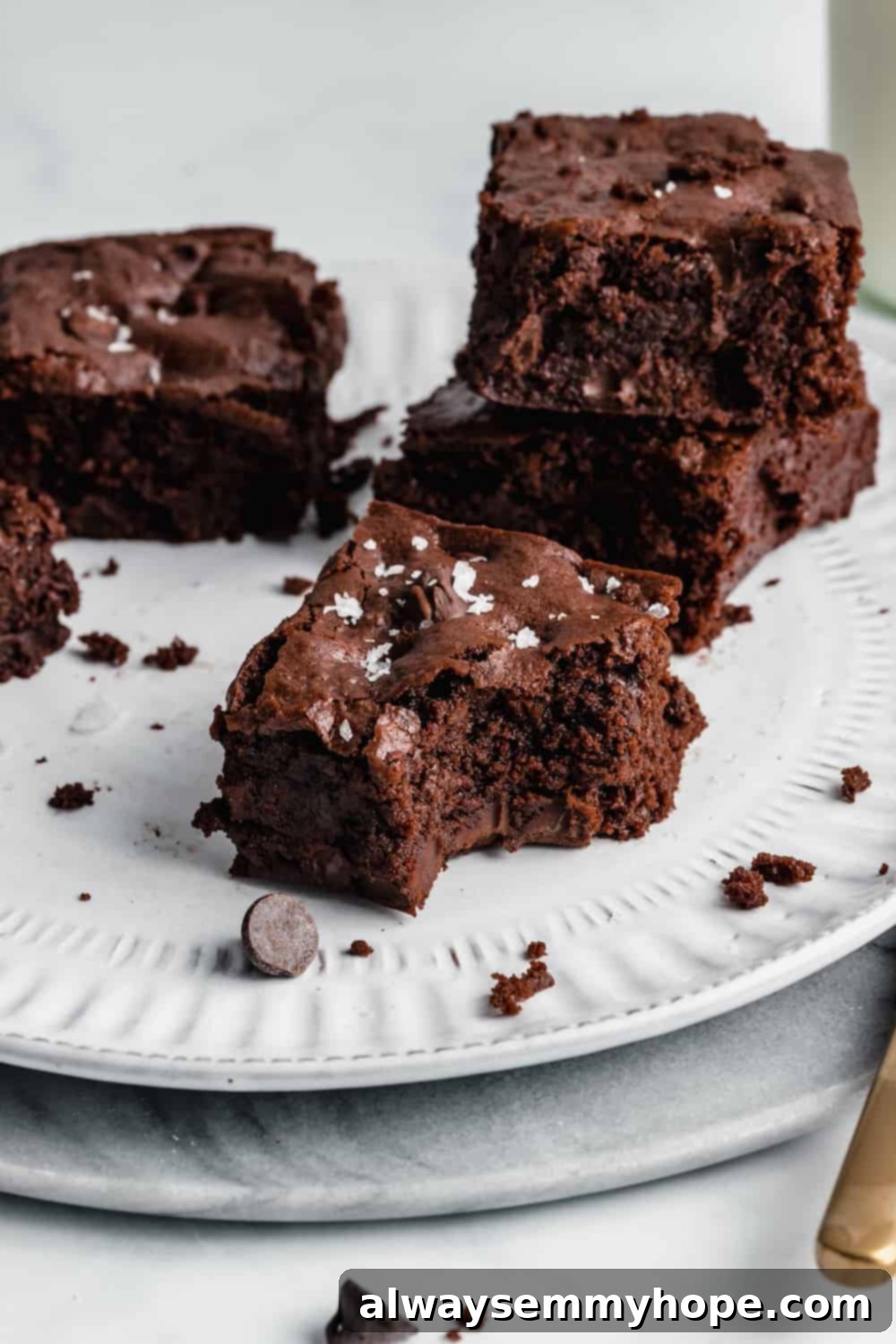 Chewy and Fudgy Vegan Brownies 10 A plate featuring a stack of three chocolate chip brownies, ready to be enjoyed.