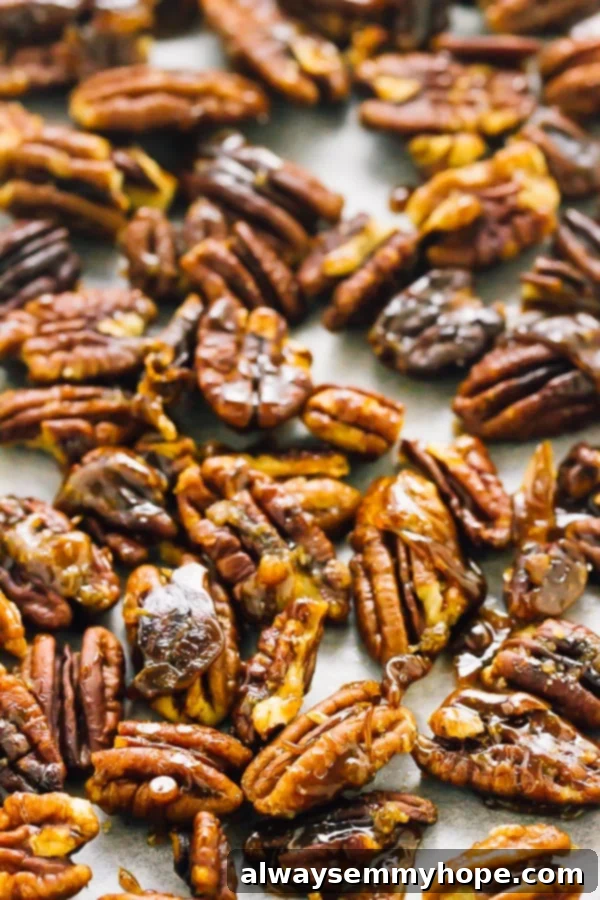 Top down shot of golden-brown candied pecans spread out on a baking tray, showcasing their shiny, sugary coating.