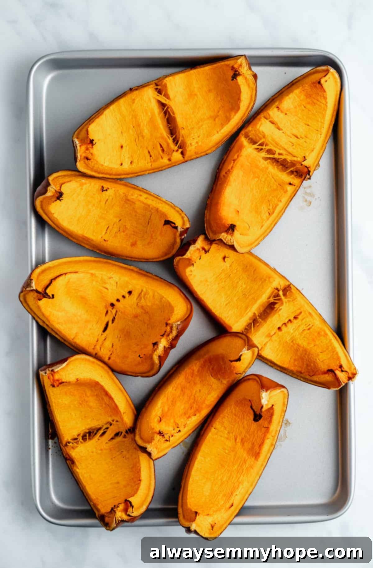 Roasted pumpkin wedges, golden-brown and tender, fresh out of the oven on a baking sheet.