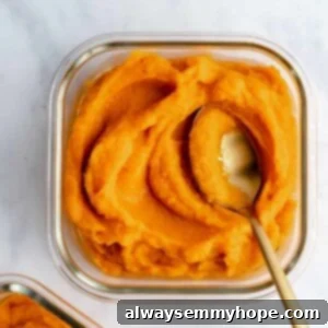 cooked pumpkin puree in a glass container with a spoon in it