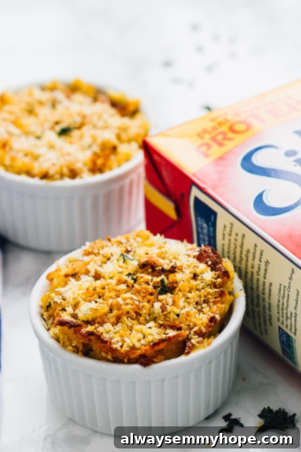 Loaded with fall flavour and a creamy, decadent texture, this Vegan Pumpkin Mac and Cheese is the perfect fall side dish. A side shot of two white ramekins filled with perfectly baked vegan pumpkin mac and cheese, showing its cheesy, golden-brown crust.
