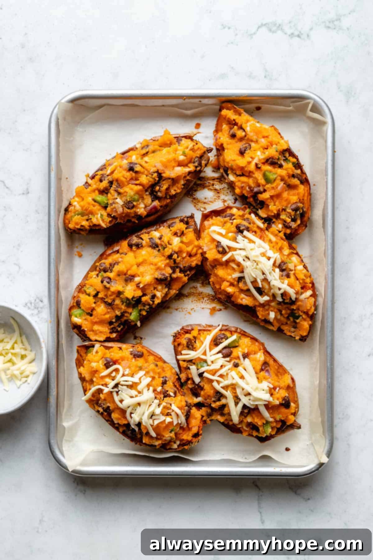 Stuffed Sweet Potato Skins 11 Overhead view of sweet potato skins on baking sheet, with half topped with shredded cheese