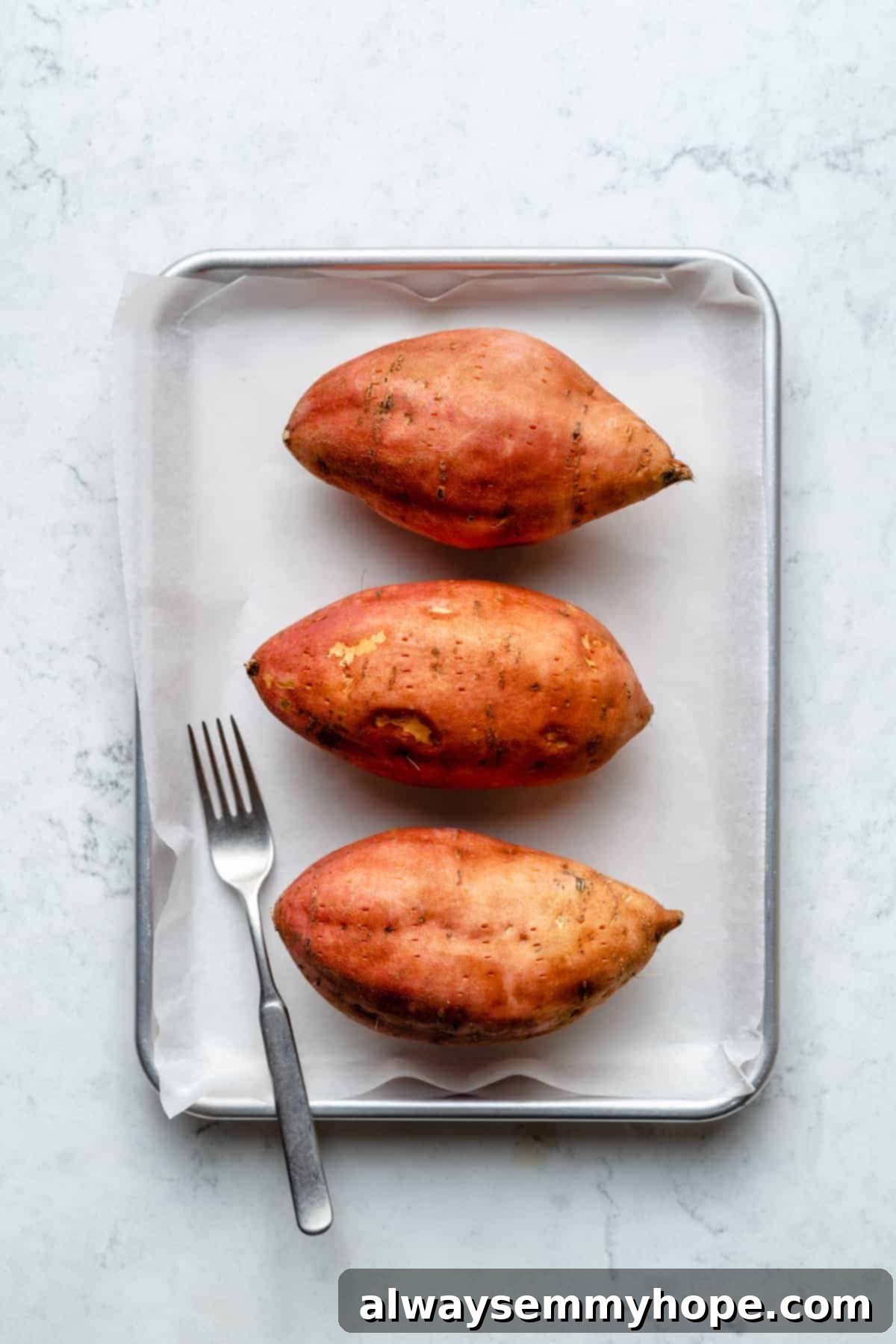 Stuffed Sweet Potato Skins 4 Overhead view of 3 sweet potatoes on baking sheet with fork