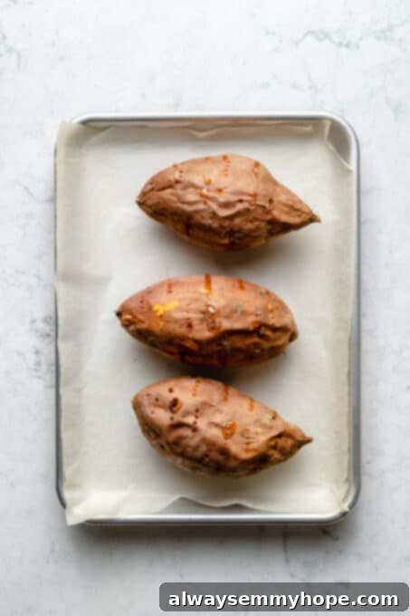 Stuffed Sweet Potato Skins 5 Overhead view of 3 baked sweet potatoes on parchment lined baking sheet