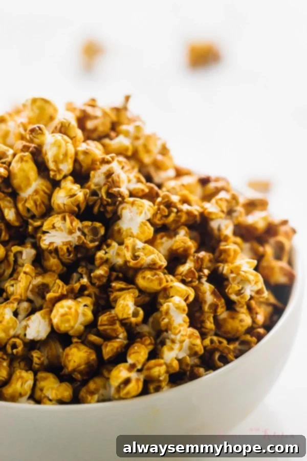 This easy vegan caramel popcorn recipe is the perfect sweet and salty snack. No corn syrup needed, and it comes together in 25 minutes! Close up of a full bowl of caramel popcorn, showcasing the rich caramel coating on each kernel.