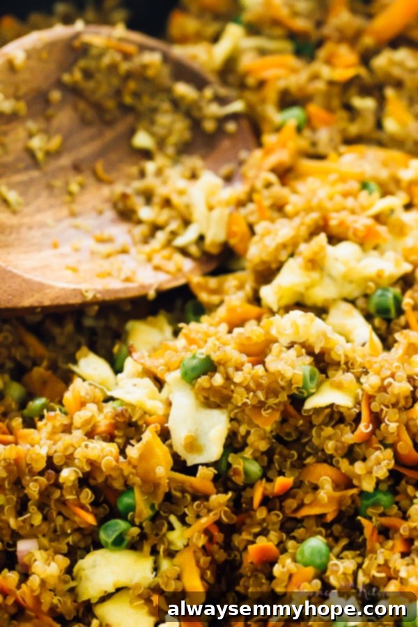 Speedy 15 Minute Quinoa Fried Rice 4 Close up of quinoa fried rice being stirred with a wooden spoon, emphasizing the texture and ingredients.