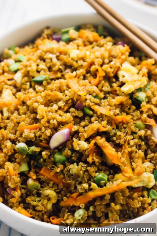 Speedy 15 Minute Quinoa Fried Rice 6 Close up of quinoa fried rice in a white bowl, ready to be eaten with chopsticks.