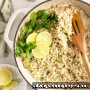Overhead view of cauliflower rice in skillet garnished with parsley sprigs and lime slices
