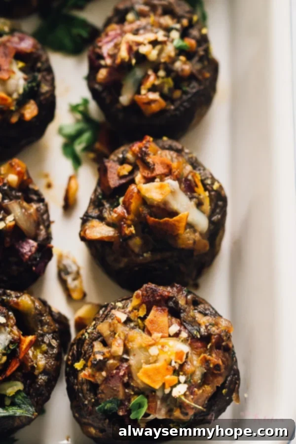 Close-up view of three stuffed mushrooms, generously topped with coconut bacon and fresh herbs.