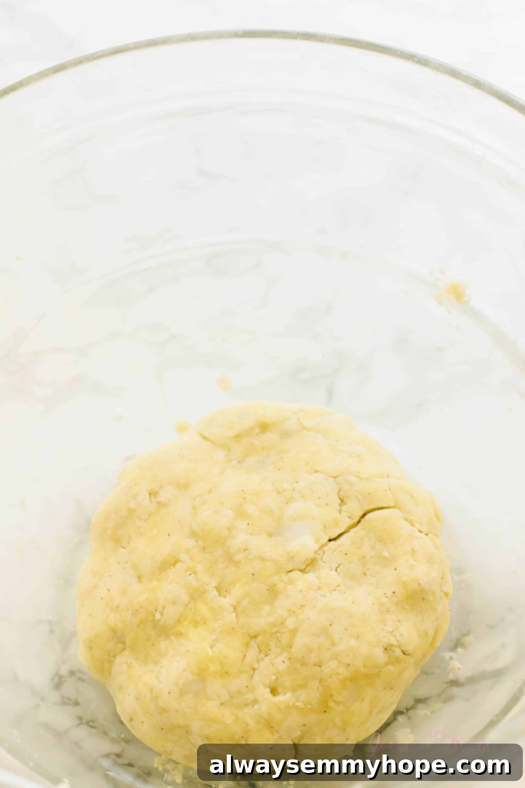 Coarsely mixed gluten-free vegan pie crust dough in a glass mixing bowl, showing visible bits of vegan butter.