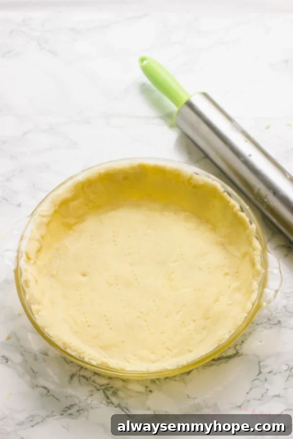 Gluten-free vegan pie crust already formed in a glass pie plate, with a rolling pin visible in the background.