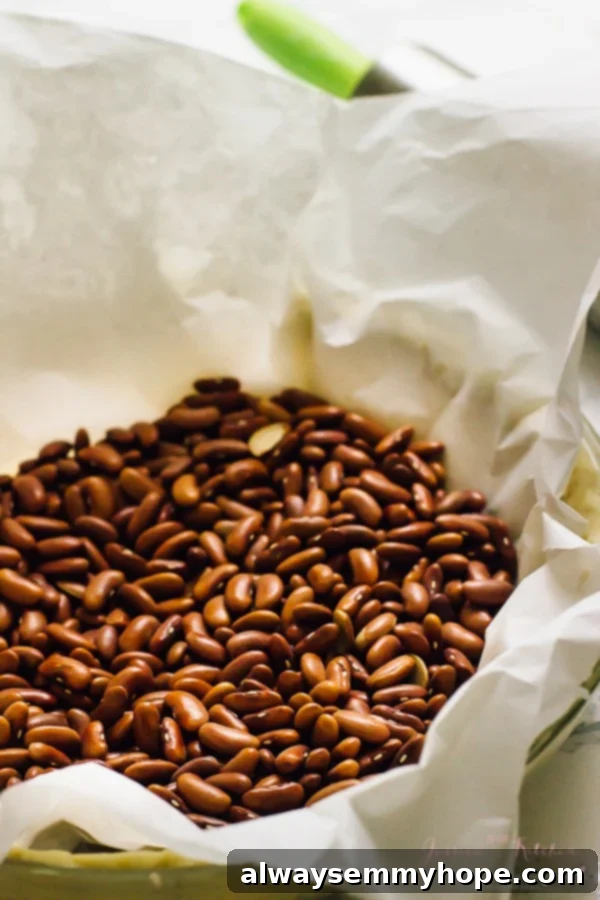 Unbaked pie crust in a pie dish, lined with parchment paper and filled with pie weights (beans) for blind baking.