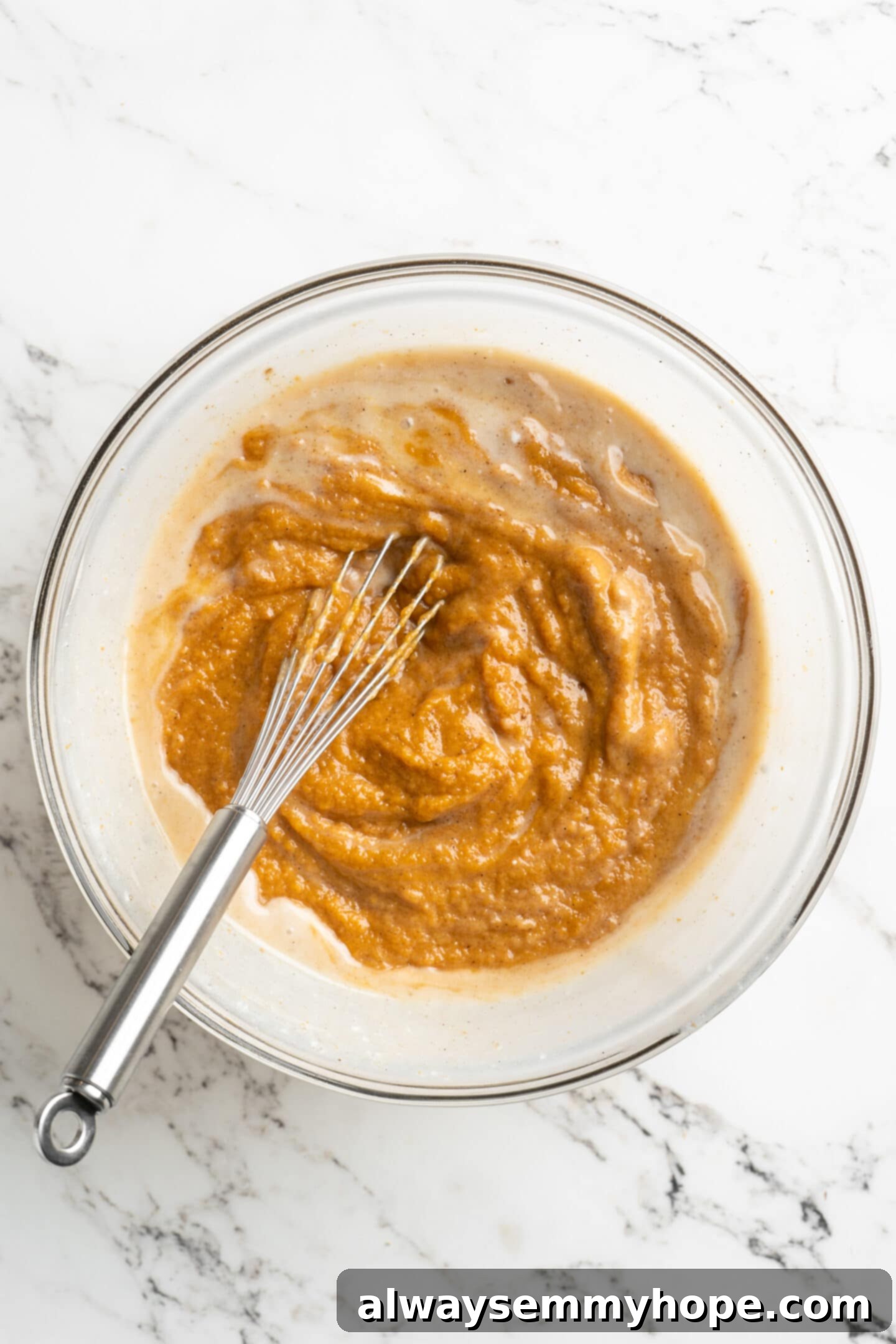 Easy 9-Ingredient Vegan Pumpkin Pie 8 mixing of pie base in a glass bowl with a whisk.